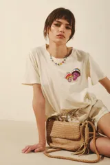 Remera color crema de manga corta con cuello redondo y estampado de hongos bordados en el frente.