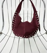 Bolso hobo color crema con tachas plateadas y cierre con botón magnético.