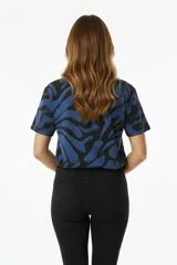 Remera de manga corta con estampado abstracto en tonos beige, marrón y negro, con cuello redondo y corte holgado.