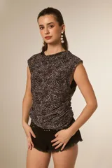 Musculosa sin mangas, ajustada al cuerpo, con estampado animal print en tonos oscuros (negro, gris, marrón) y detalle de drapeado en el frente. Posee cuello buche.