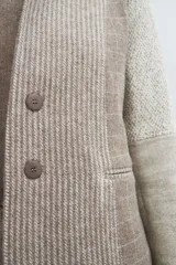 Chaqueta corta color marrón con cuello solapa y diseño con patchwork de telas. Manga larga con detalle de coderas aplicadas. Cierre frontal mediante botones y bolsillos ojal. Con forro.