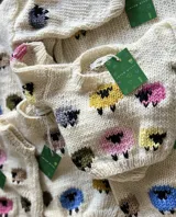 Sweater de lana color crema con cuello redondo y diseño de ovejas de colores bordadas a mano.