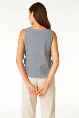 Blusa sin mangas con estampado a rayas verticales en tonos blanco, azul y verde. Presenta cuello redondo y lazos laterales.