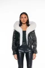 Campera corta negra de cuero sintético con capucha y cuello de piel sintética blanca desmontable, cierre frontal con cremallera, bolsillos delanteros con solapa y puños ajustables con botones a presión.