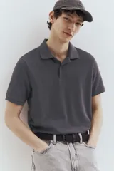 Remera polo gris de piqué de algodón, de manga corta, con cuello clásico, tapeta de botones, remate acanalado en cuello y mangas, bajo recto con aberturas laterales y corte estándar.