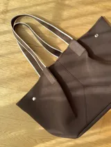 Bolso negro tipo tote de neopreno con bolsillo interno de red, sobre haciendo juego y gancho para sujetarlo.