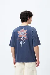 Remera azul con efecto gastado, corte holgado y estampado pequeño de flor en el pecho.