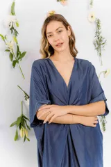 Vestido azul denim con escote en V, mangas cortas y detalle de nudo en la cintura.