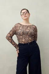 Top de manga larga en tejido translúcido con estampado animal print en tonos marrones y negros. Diseño ajustado con transparencia.