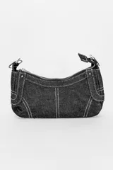 Cartera negra de denim con costuras blancas en contraste, cierre superior con cremallera y asa corta con hebilla ajustable.