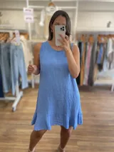 Vestido corto blanco, sin mangas, de corte suelto y con un volante en el ruedo.