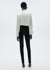 Pantalón negro de tejido de punto ligero con cintura elástica, corte slim fit, diseño largo, detalle de costuras y cierre con cremallera en los bajos.