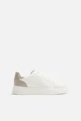 Zapatillas deportivas blancas con detalle en color gris en el talón y suela con plataforma.