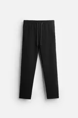 Pantalón negro de corte recto, con cintura elástica ajustable con cordón, bolsillos frontales y traseros.