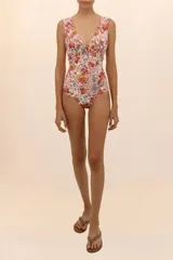 Traje de baño entero con estampado floral en tonos naranja, amarillo y celeste. Tiene escote en V y cintura fruncida.