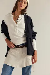 Camiseta tipo henley de manga larga, color blanco, confeccionada en algodón elástico con cuello redondo y tapeta de botones.