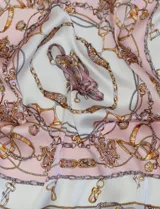 Pañuelo cuadrado de satén con estampado de cadenas doradas y detalles en rosa y blanco.