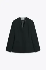 Blazer negra entallada, de escote pico y manga larga con hombreras. Tiene bolsillos delanteros de vivo y cierre frontal con botones a presión ocultos.