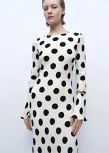 Vestido midi blanco con lunares negros, de mangas largas acampanadas y cuello redondo.