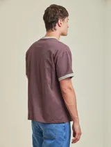 Remera azul de corte holgado con cuello y mangas con ribete rojo y logo estampado en el pecho.
