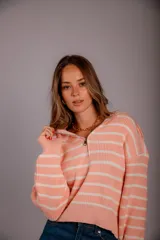 Sweater de punto color beige con rayas horizontales blancas, cuello polo con cierre de cremallera y mangas largas.