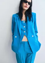 Chaleco azul con tirantes finos, escote cuadrado, cierre frontal con botones y espalda descubierta.