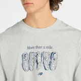 Remera de manga corta color gris melange con cuello redondo. Estampado frontal con la frase "More than a mile." y un dibujo lineal de cuatro zapatillas deportivas, con el logo de New Balance debajo.