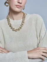 Sweater de lurex color gris con brillo dorado, de cuello redondo y mangas largas.