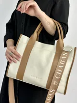 Bolso tote color crema con detalles en cuero marrón. Tiene doble asa de mano y correa de hombro extraíble con el logo de la marca.