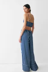 Pantalón de corte holgado en sarga con estampado a rayas verticales azules y blancas. Modelo de talle alto con cintura elástica y cordón de ajuste fino.