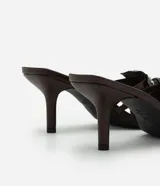 Sandalia mule color marrón con punta cuadrada, tira con flor y aplicación de strass, y tacón fino alto.