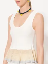 Top blanco sin mangas con detalle de volados plisados en el ruedo.