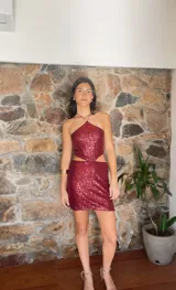 Minivestido borgoña de lentejuelas con escote halter, espalda descubierta y aberturas laterales en la cintura.