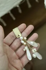 Aros colgantes con base dorada y apliques de perlas de río y cuentas de cristal.