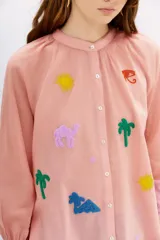 Camisa de algodón color rosado con bordados inspirados en Egipto, de corte amplio y escote redondo.