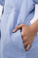 Camisa celeste de mangas largas con puños abotonados, cuello clásico y cierre frontal con botones.