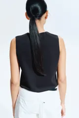 Chaleco negro de punto con cuello redondo y cierre frontal con botones dorados.