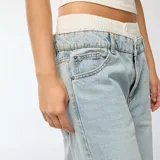 Pantalón jean celeste de corte ancho, tiro alto y efecto calzoncillo a la vista.