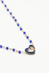 Collar corto con cadena de cuentas facetadas color azul y dije central de corazón con detalle floral.