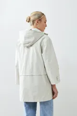 Campera impermeable gris claro con capucha plegable y bolsillos laterales.