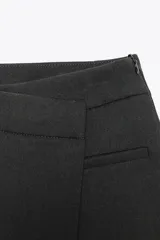 Falda pantalón corta color crudo, de tiro medio y cintura asimétrica cruzada.
