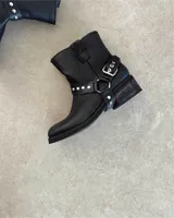 Botín de cuero vacuno negro de caña corta con hebilla y tachas plateadas.