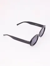 Lentes de sol ovalados con montura gruesa de acetato color negro y cristales grises. Diseño retro.