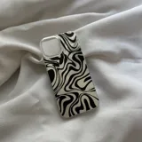 Funda protectora para celular, transparente en los bordes, con diseño abstracto de líneas onduladas en blanco y negro, similar a un patrón de cebra o remolino psicodélico.