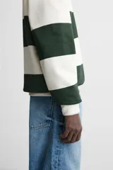 Sudadera tipo polo con cuello clásico, manga larga y diseño a rayas horizontales en color verde oscuro y crudo.