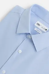 Camisa celeste de corte slim fit, confeccionada en tejido de algodón. Tiene cuello italiano, mangas largas con puños abotonados y cierre frontal con botones.
