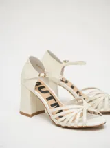 Sandalias negras de charol con tiras cruzadas en el empeine, pulsera con hebilla al tobillo y tacón cuadrado.