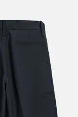 Pantalón de vestir azul marino, de corte recto, con bolsillos laterales y traseros. Incluye un bolsillo tipo cargo en la pierna izquierda. Se ajusta a la cintura con cinturón de cuero marrón.
