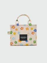 Bolso tote pequeño de lona color crema con estampado de margaritas de colores, doble asa superior y correa bandolera ajustable y extraíble.
