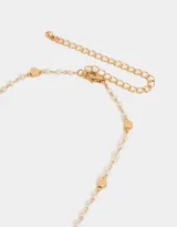 Collar corto dorado con cadena de perlas y dijes de corazones.